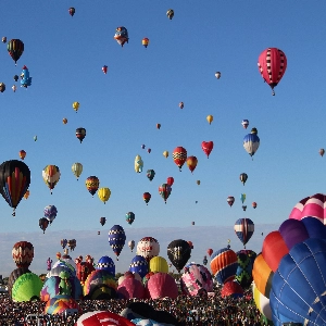 Crowd enjoying the colorful spectacle at Albuquerque International Balloon Festival, with numerous hot air balloons dotting the sky