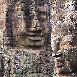 Ancient Bayon Temple with majestic stone faces and intricate carvings, nestled in lush green surroundings.