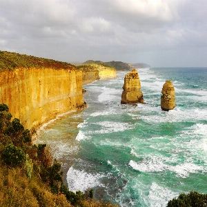 Scenic view of the Great Ocean Road, winding along the coastline with turquoise waters and lush greenery