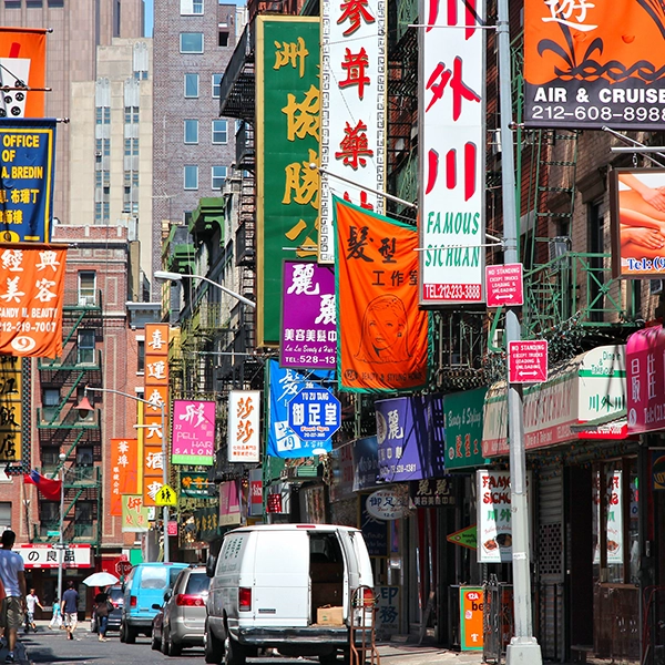 Vibrant street scene in Chinatown, New York, with busy shops, colorful signs, and pedestrians enjoying the lively atmosphere