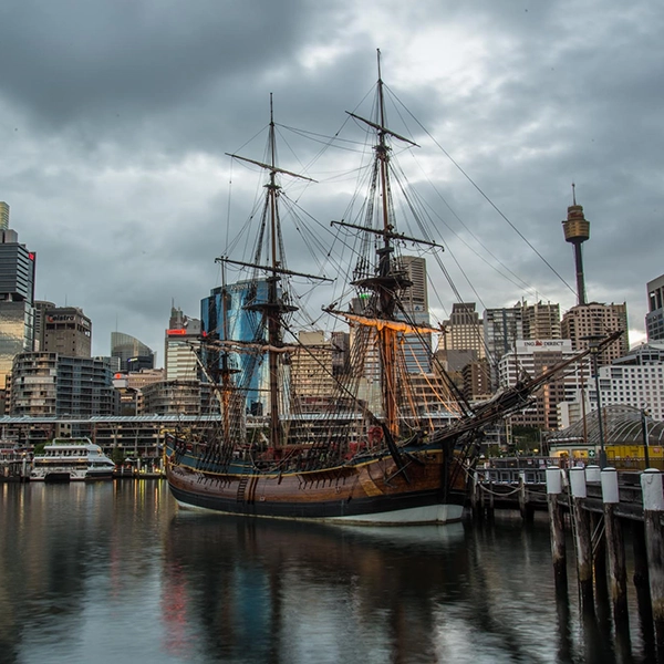 Panoramic view of Darling Harbour with its bustling waterfront, featuring boats, restaurants, and shimmering city skyline