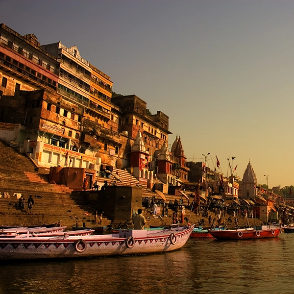 Scenic view of the historic ghats of Varanasi, India, with steps leading to the Ganges River and colorful buildings along the riverbank.