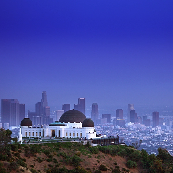 A stunning view of Griffith Observatory, an iconic Los Angeles landmark, situated atop a hill with a beautiful cityscape backdrop